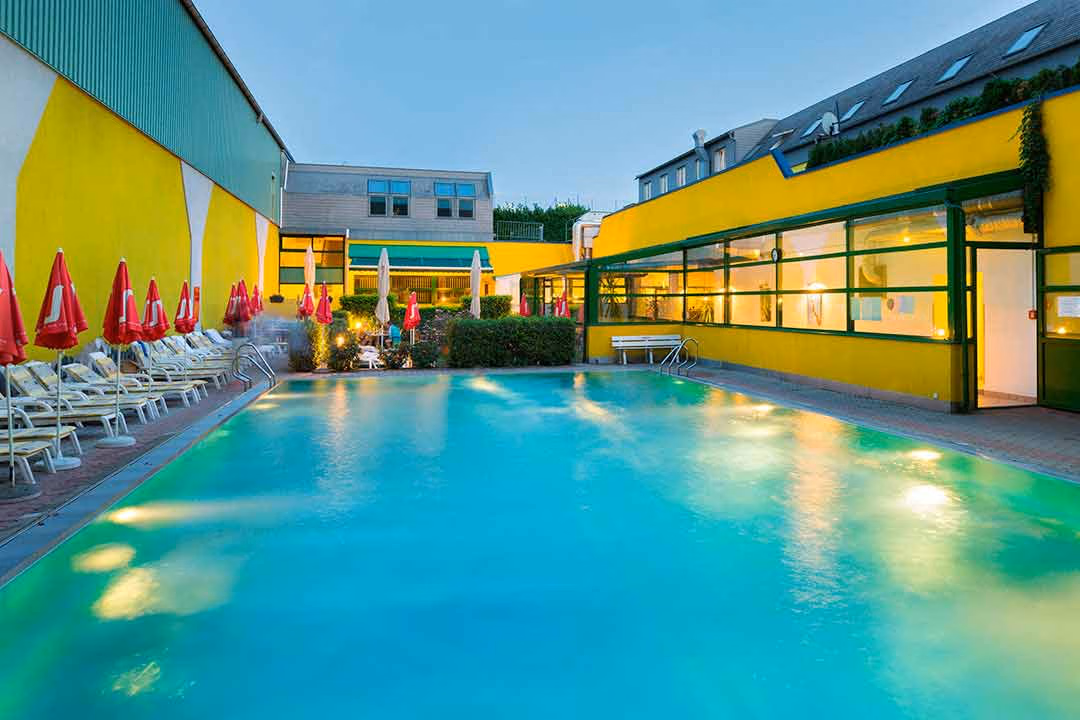 Außenansicht unseres Hotelpools inklusive der Gästeliegen und Ruheraums des Wellnessbereichs